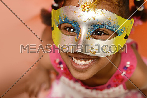 An african little girl wearing a venetian style mask