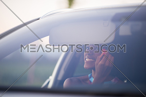young beautiful African American woman making makeup while driving car