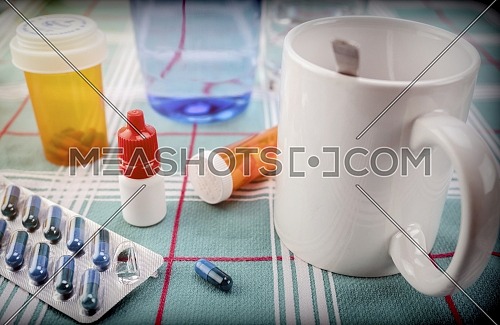 Medication during breakfast, capsules next to a glass of water, conceptual image, horizontal composition