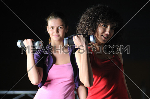 two girls working out with dumbbell in fitness club