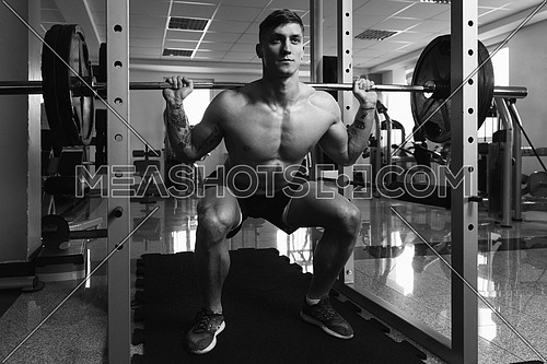Healthy Fitness Man Working Out Legs With Barbell In A Gym - Squat Exercise