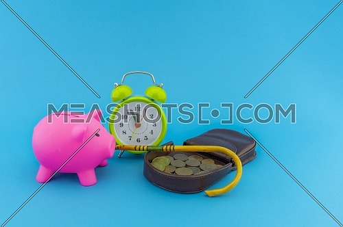 Saving for old-age and retirement concept with open purse with coins, walking stick, alarm clock and piggy bank over a blue background with copy space