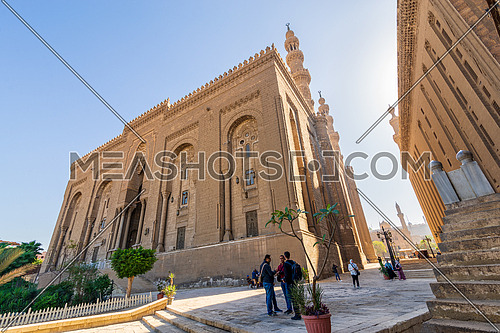 Cairo, Egypt - November 27 2021: Facade of Islamic Royal era Mosque of Al Rifai, with side view of Mamluk era Mosque and Madrassa of Sultan Hassan, with few visitors, Old Cairo