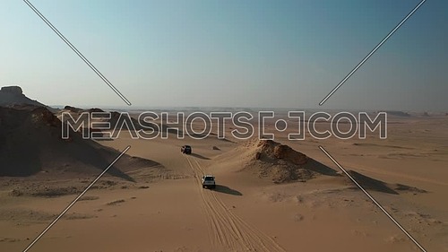 Aerial shot for Two 4x4 Cars moving through sand dunes in the desert at day