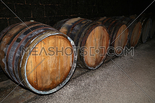 Close up rows of traditional aged natural oak wood wine barrels in winery cellar