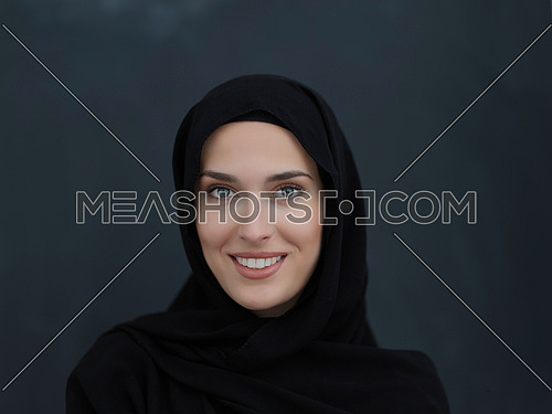 Portrait of modern young muslim woman in black abaya. Arab girl wearing traditional clothes and posing in front of black chalkboard. Representing modern and rich arabic lifestyle