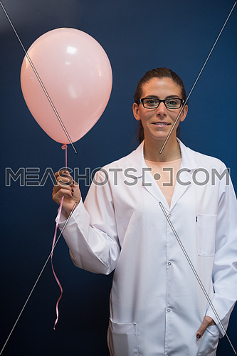 portrait of a young middle eastern female doctor in office holding pink balloon for cancer awarness