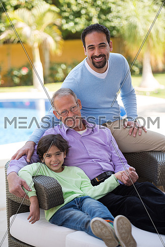 portrait of middle eastern grandfather with his son and grandson to enjoy a sunny summer morning at the pool