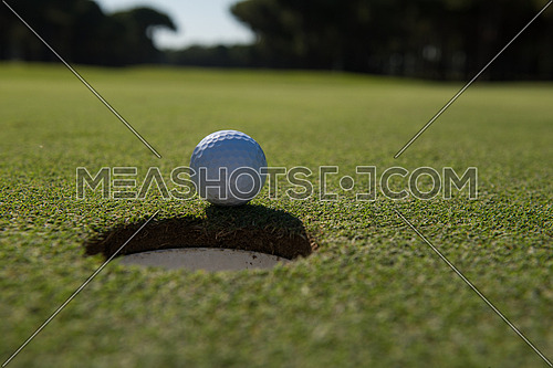 golf ball on edge of course hole representing achivement and success business concept