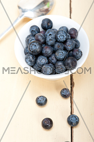 fresh blueberry on a bowl with silver spoon over wood table