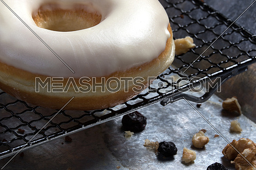 top side view  of white glazed donuts with walnuts aside, hazelnuts