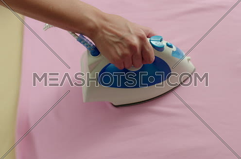 Close and Follow Shot for A female hand Ironing pink Shirt