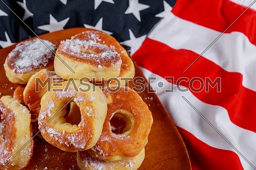 Donut with powdered sugar and american flag on wood dish, american independence day, celebration, patriotism and holidays concept