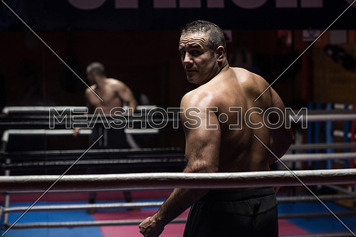 portrait from the back of muscular professional kickboxer who standing in the ring while training for the fight