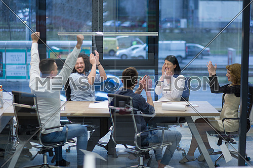 Group of young business people looking happy while celebrating success at their working places in startup office