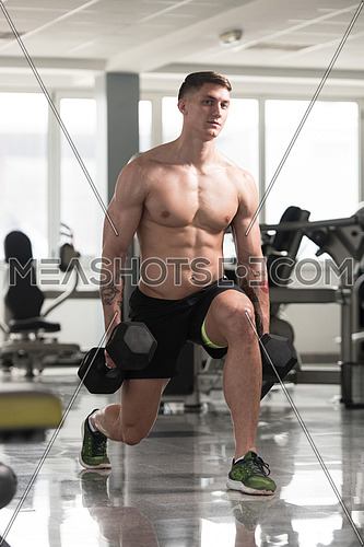 Young Man Working Out Legs With Dumbbells In A Gym - Squat Exercise
