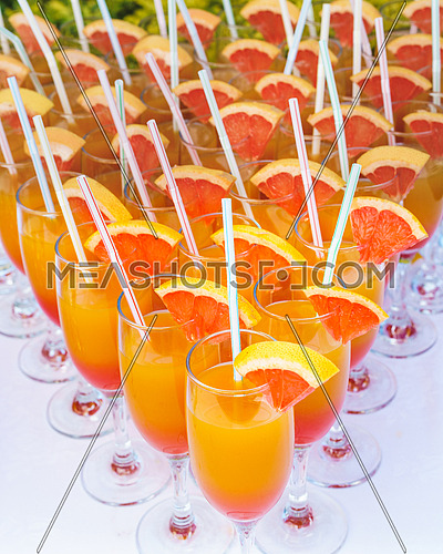 Orange juice cocktail in a flute glasses and slice of fresh orange with draw on white table,closed picture.