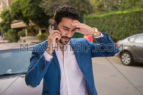 A young man is talking in the mobile phone in the street and he is angry