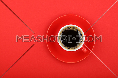 One full morning Americano black coffee with froth edge in small red cup with saucer on red paper background, top view, bird eye view