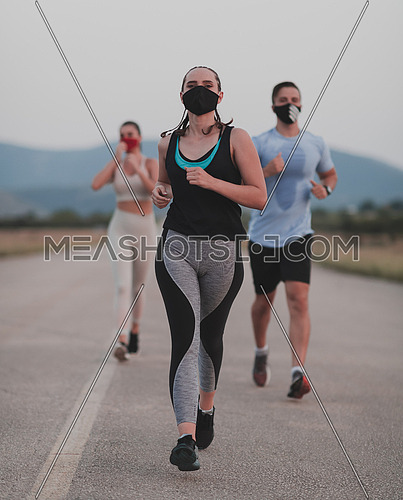 Multiethnic runners group wear face masks running keep social distance outdoor. Fit healthy diverse team wears sportswear jogging in the evening on nature sports track distancing for safety.