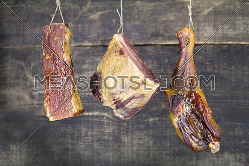 Smoked Pork and Chicken Meat Hanging on the Rope Against Wooden Background