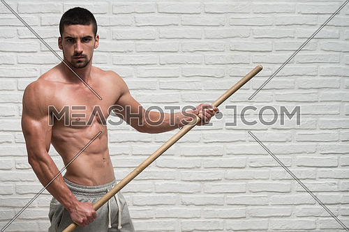 Athlete Muscular Bodybuilder Emotional Posing At The Wall With Stick