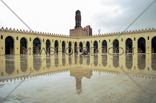 Hakim Be Amr-allah mosque on  a rainy day with a full reflection of the mosque on the marble floor.