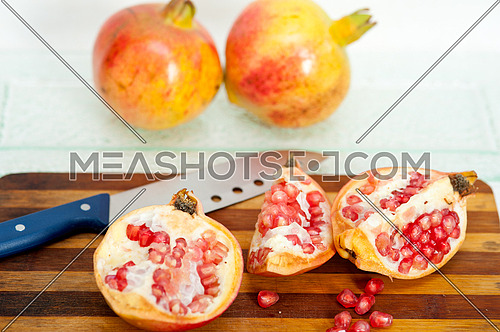 fresh pomegranate fruit over wood cutting board with knife