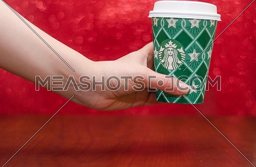 Starbucks takeaway paper cup, in special design for Christmas on a festive red background; December 2018 - Cairo, Egypt