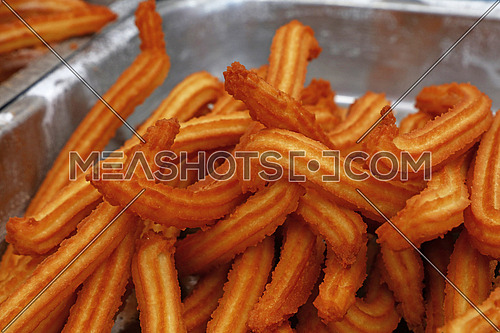 Sweet fresh churros, traditional Spanish or Portuguese deep fried dough pastry snack cooked close up, high angle view