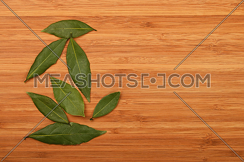 Group of several bay laurel leaves on bamboo wooden chopping board background