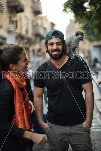 two young middle eastern tourists enjoy playing with a monkey in the city