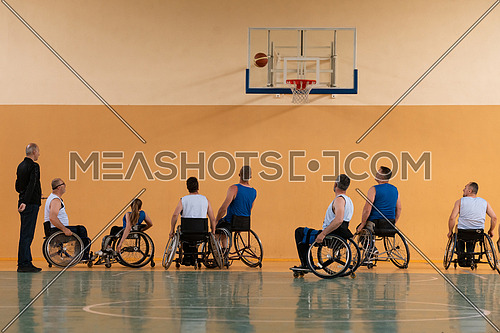 Disabled War veterans mixed race opposing basketball teams in wheelchairs photographed in action while playing an important match in a modern hall. High quality photo.