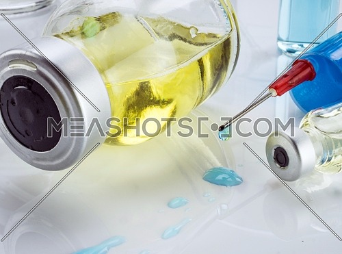 Plastic glass with daily medication along with to a syringe, conceptual image