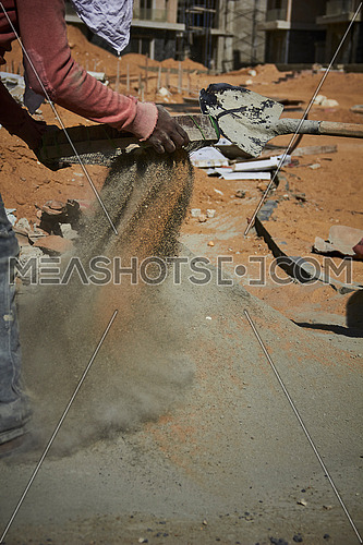 Mid Shot for worker sifting Cement in a construction site at day