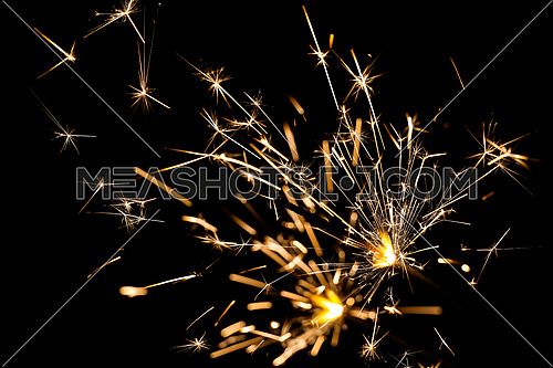 Close up ggroup of several bright firework sparklers over black, background for Christmas, wedding and Independence Day, low angle side view
