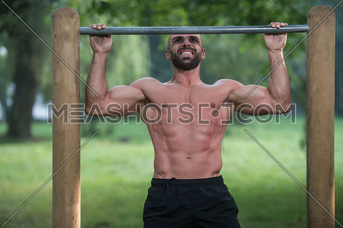 Muscular Built Young Athlete Working Out In An Outdoor Gym - Doing Chin-Ups