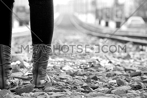 Girl wearing boots standing on stones shot from behind