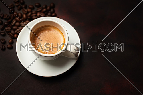 White cup of coffee and coffee bean on dark background. Copy space.