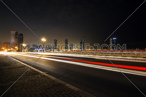 highway by night showing an urban modern cityscape and car lights in long exposure speed concept