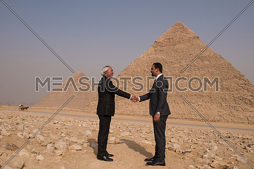 successful arab business people shaking hands over a deal with Egyptian giza pyramids in backgronud