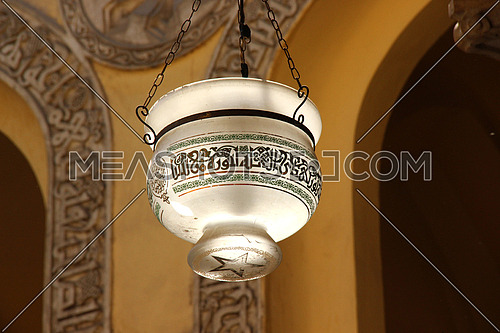 a photo from inside AL Aqmar mosque in Islamic Cairo, Egypt  showing part of the ceiling and traditional lamp post used for lighting at that time