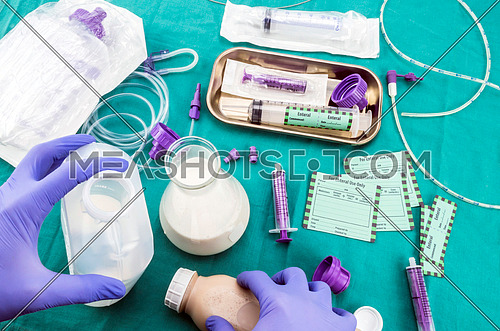 Nurse preparing bottle supply in team of enteral nutrition, palliative care in hospital, conceptual image, composition hotizontal