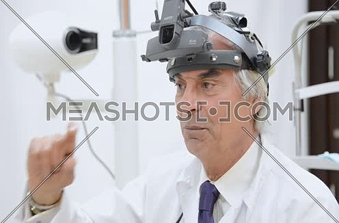 middle eastern senior ophthalmologist checking patient eyes