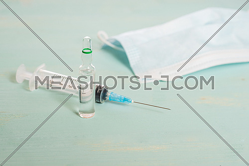 Medical vials,medical mask and syringe isolated on green background, vaccination concept and disease treatments