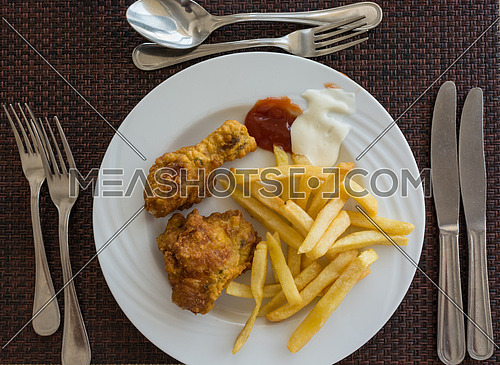 Pictured fried chicken with chips served on white dish at the restaurant, view from above.