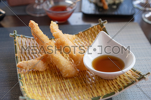 Three Shrimps tempura with soy sauce on yellow bamboo plate. Seafood tempura dish of traditional asian cuisine