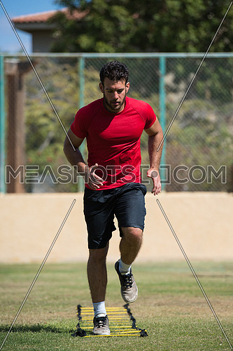 young middle eastern man athlete running and exercise to speed ladder out in the field on a sunny day