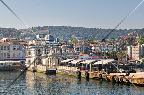 Istanbul, Turkey - April 27, 2017: Buyukada (Princess Island) Ferry Terminal with passengers riding a ferry and summer houses, and green mountains in the background, Istanbul, Turkey