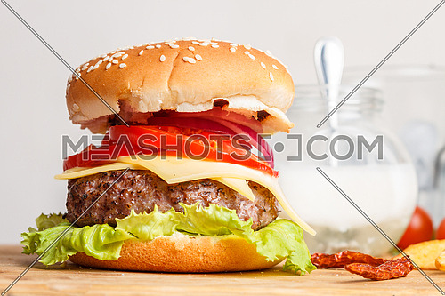 Burger sandwich on a wooden tray with garnish elements